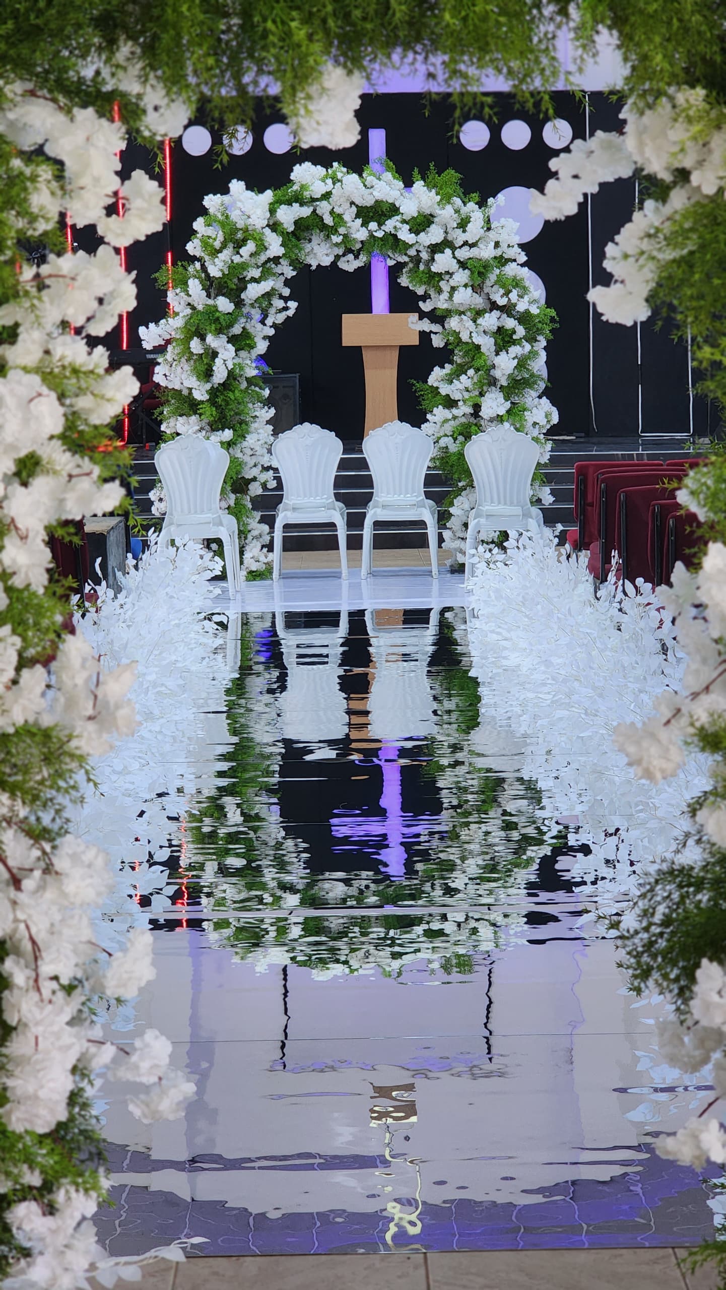 White floral wedding aisle framed by greenery